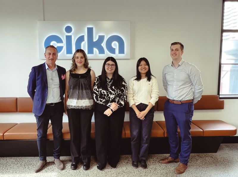 Group of people standing under Cirka sign.