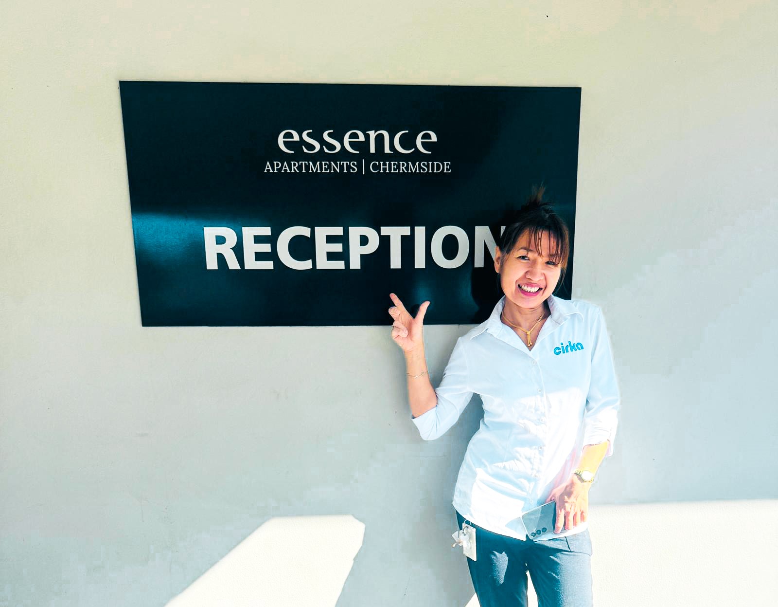 Cirka Employee in front of the Essence Hotel sign